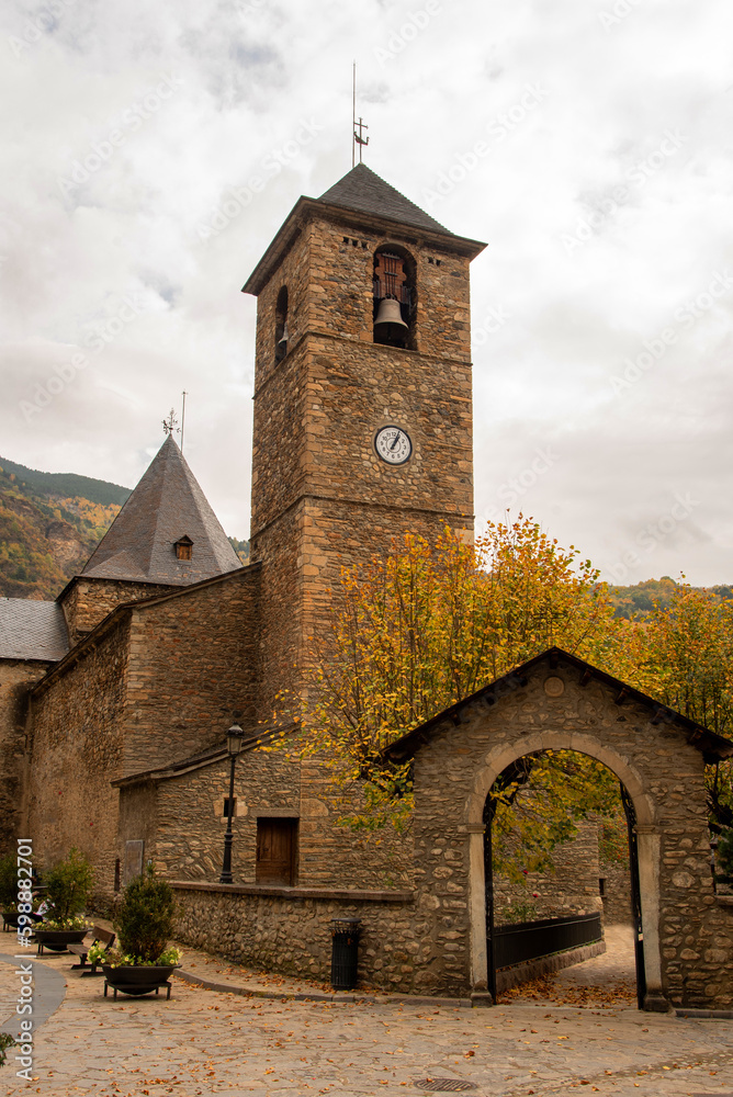 Detail plan of the church Santa María la Mayor built in stone and slate and surrounded by trees in the touristic village of Benasque, located in the middle of large mountains, Huesca, Aragón.