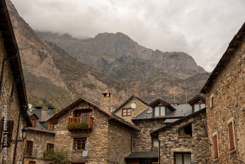 Detailed plan of the slate roofs of the small houses with stone architecture and in the background large mountains in the tourist village of Benasque, in Huesca, Aragon.