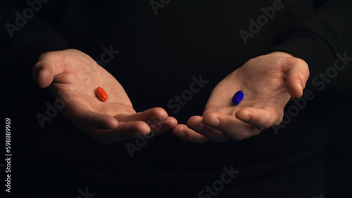 Studio shot hands show red pill and blue pill isolated on black background. Concept of making right choice.