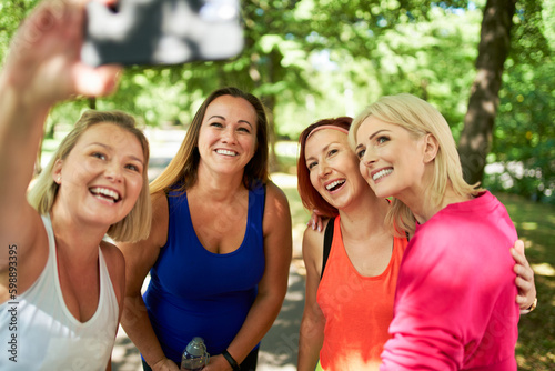 Group of happy active women from fitness class taking selfie in the park