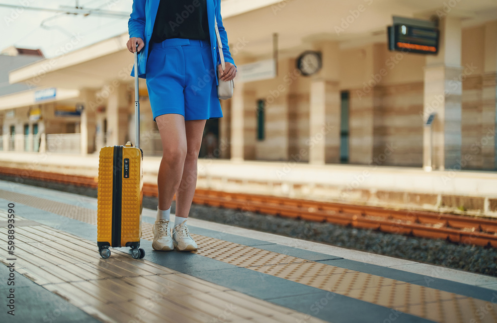 Obraz premium Woman with travel suitcase is waiting for a train.
