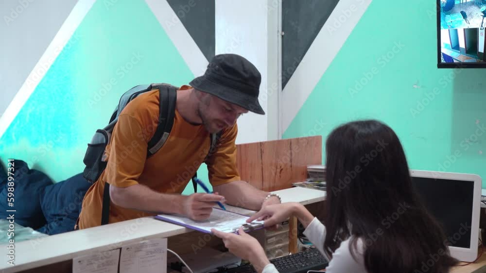 Caucasian man traveling alone register or check in at hostel, receptionist giving information sitting at counter welcoming new customer. lifestyle backpacker traveling low cost expenses concept.
Caucasian man traveling alone register or check in at hostel, receptionist giving information sitting at counter welcoming new customer. lifestyle backpacker traveling low cost expenses concept.