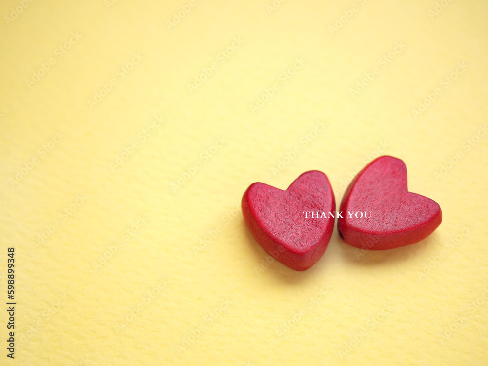 Fototapeta premium The words thank you message and two red heart on the yellow paper background. top view, flat lay with copy space. Greeting card