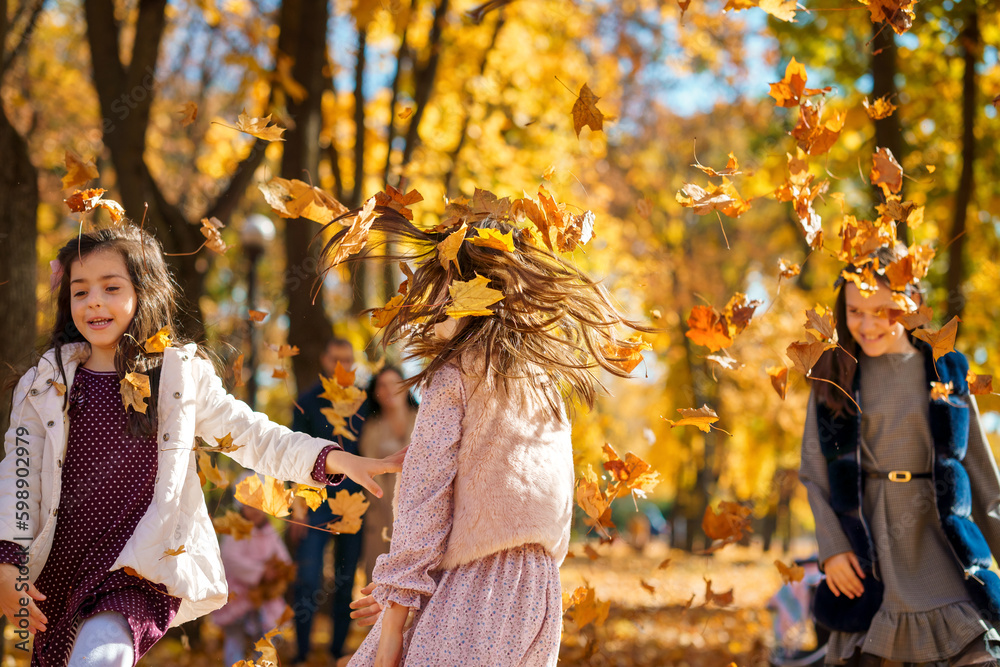 happy children playing together and scattering yellow leaves, portrait of big family in autumn city park, children running with armful of leaves, beautiful nature, bright sunny day