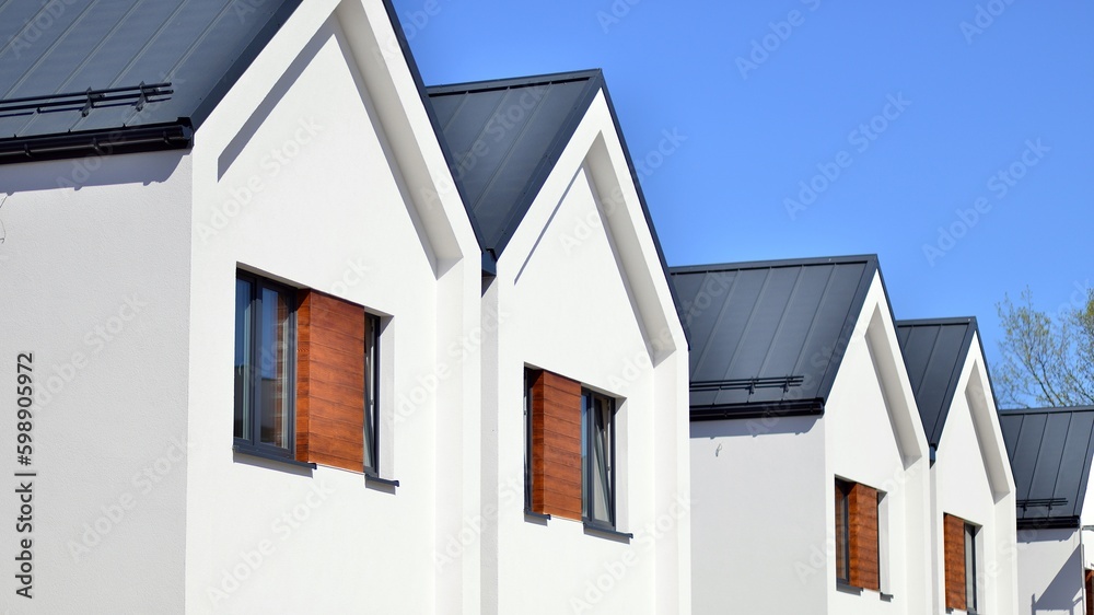 Terraced family homes in newly developed housing estate. The real estate market in the suburbs. New single family houses in a new development area. Residential homes with modern facade. 