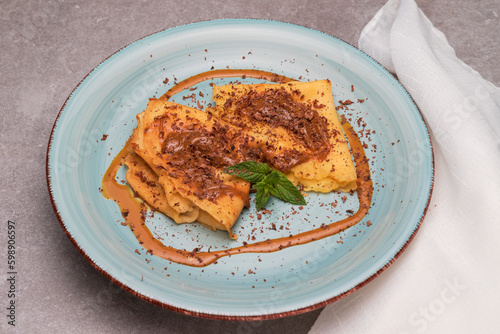 Sauce caramel and chocolate crepes on a light blue plate