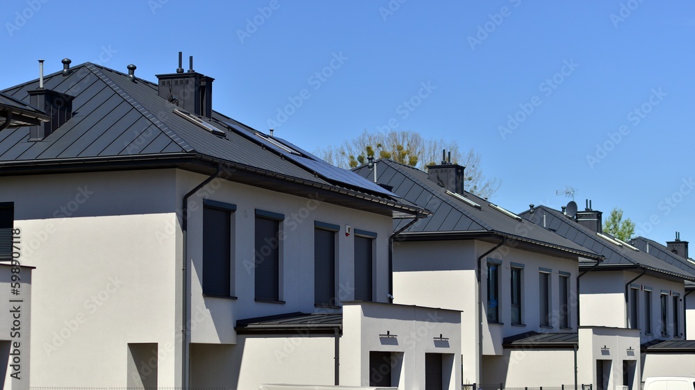 Terraced family homes in newly developed housing estate. The real estate market in the suburbs. New single family houses in a new development area. Residential homes with modern facade. 