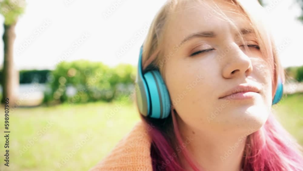 Portrait of a young laughing girl with braces listening to music in headphones in the summer on the street Portrait of a young laughing girl with braces listening to music in headphones in the summer on the street