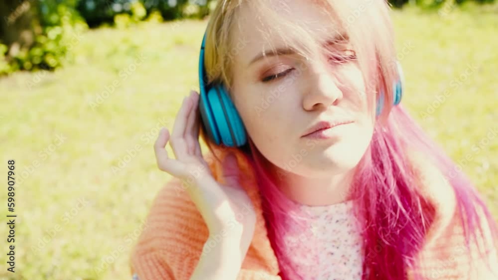 Portrait of a young laughing girl with braces listening to music in headphones in the summer on the street Portrait of a young laughing girl with braces listening to music in headphones in the summer on the street