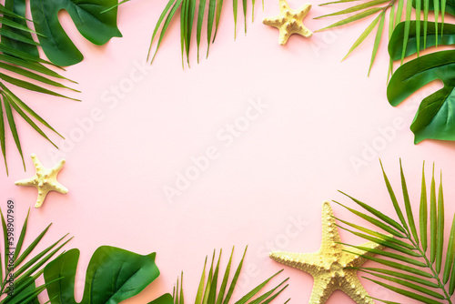 Summer flat lay on pink background. Tropical leaves, palm leaves and sea shells.