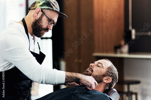 Youre in safe hands with him. a handsome young barber trimming and lining up a clients beard inside a barbershop.