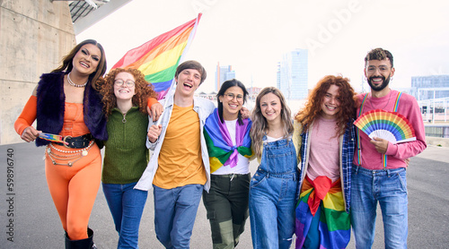 Group of young cheerful friends strolling together on day of gay pride parade in city. People LGBT community pose hugging looking smiling at camera outdoor. Generation z photo