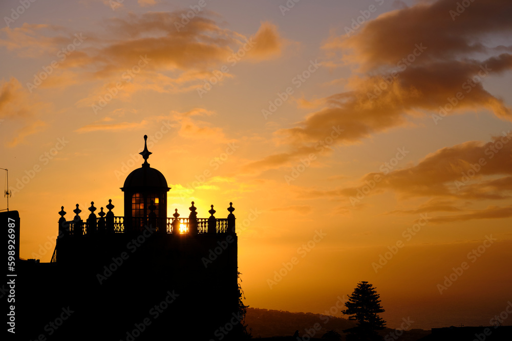 Silhouette of building with old tower against sunset sky