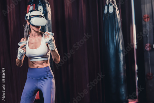 Fototapeta Naklejka Na Ścianę i Meble -  Fitness lovers battle against other gym members by wearing virtual reality goggles during intense boxing exercises. Learning and improving boxing techniques, from simple strikes to complex combos