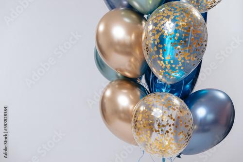 Blue and golden balloons on white background on the right. Copy space. 
