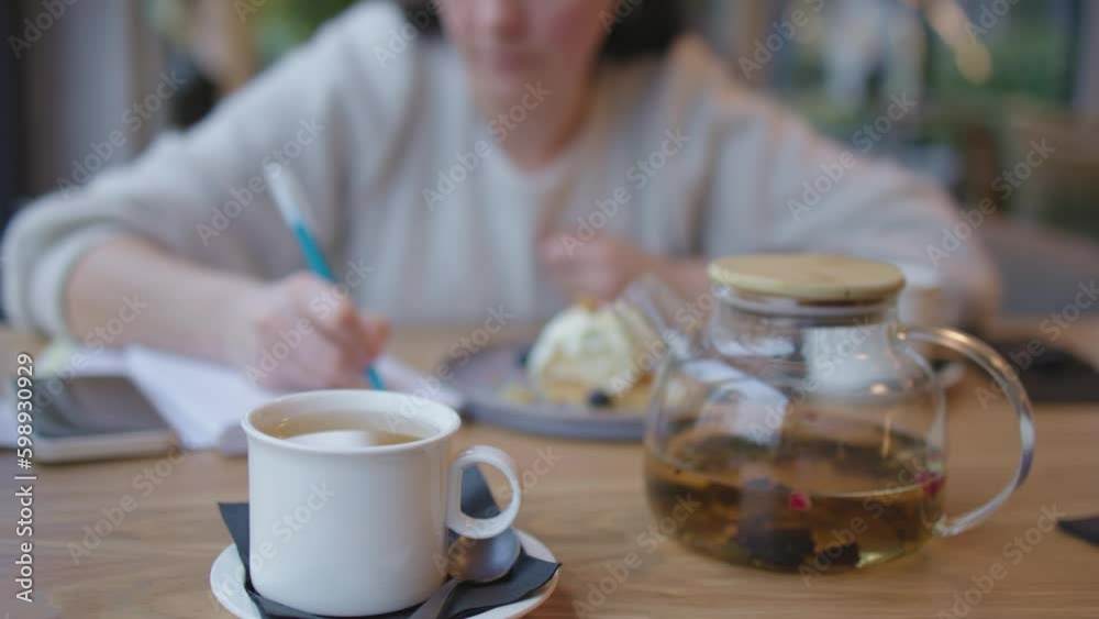 female in white working in cafe while having lunch or breakfast tea coffee cup and cake on plate. woman writing notes on paper holding blue pen in hands. businesswoman break, student in Generative AI female in white working in cafe while having lunch or breakfast tea coffee cup and cake on plate. woman writing notes on paper holding blue pen in hands. businesswoman break, student in Generative AI