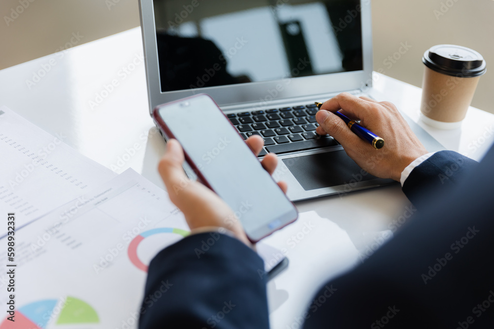 Asian businessman working at office with laptop, tablet and graph data sheet on his desk. Asian businessman working at office with laptop, tablet and graph data sheet on his desk.
