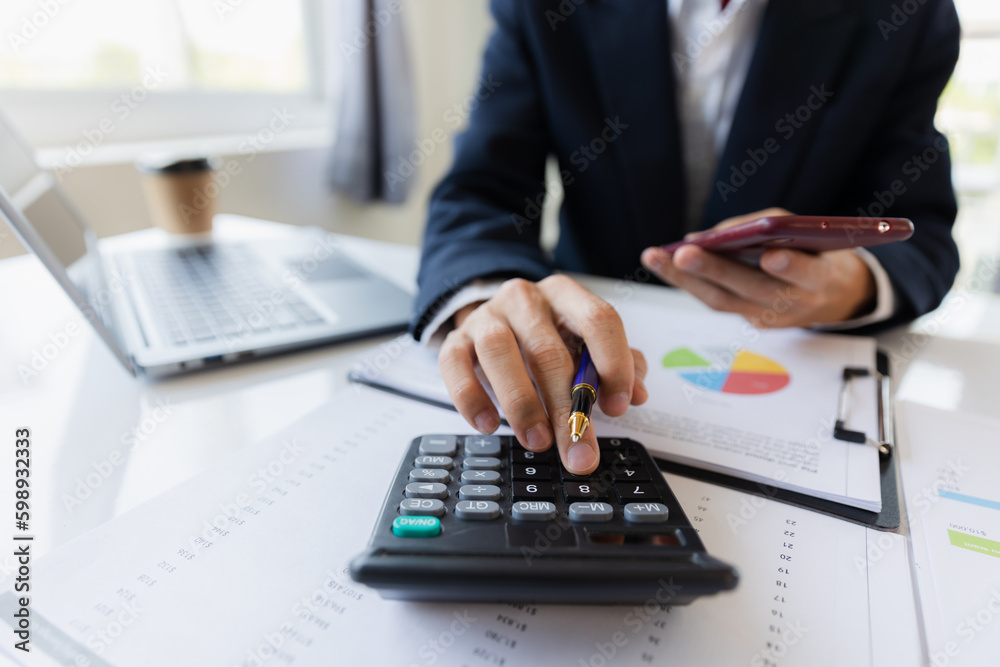 Asian businessman working at office with laptop, tablet and graph data sheet on his desk. Asian businessman working at office with laptop, tablet and graph data sheet on his desk.