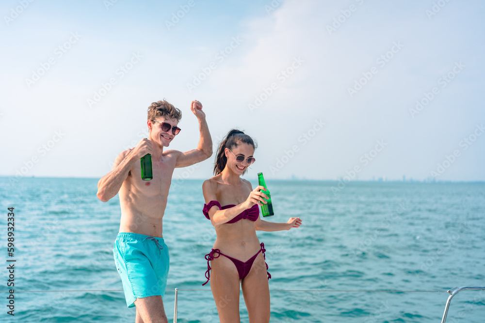 Portrait of happiness Caucasian couple drinking beer to party in yacht. Attractive man and woman hanging out celebrating anniversary in honeymoon trip while catamaran boat sailing during summer sunset