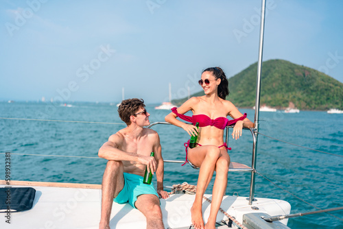 Portrait of happiness Caucasian couple drinking beer to party in yacht. Attractive man and woman hanging out celebrating anniversary in honeymoon trip while catamaran boat sailing during summer sunset © chokniti