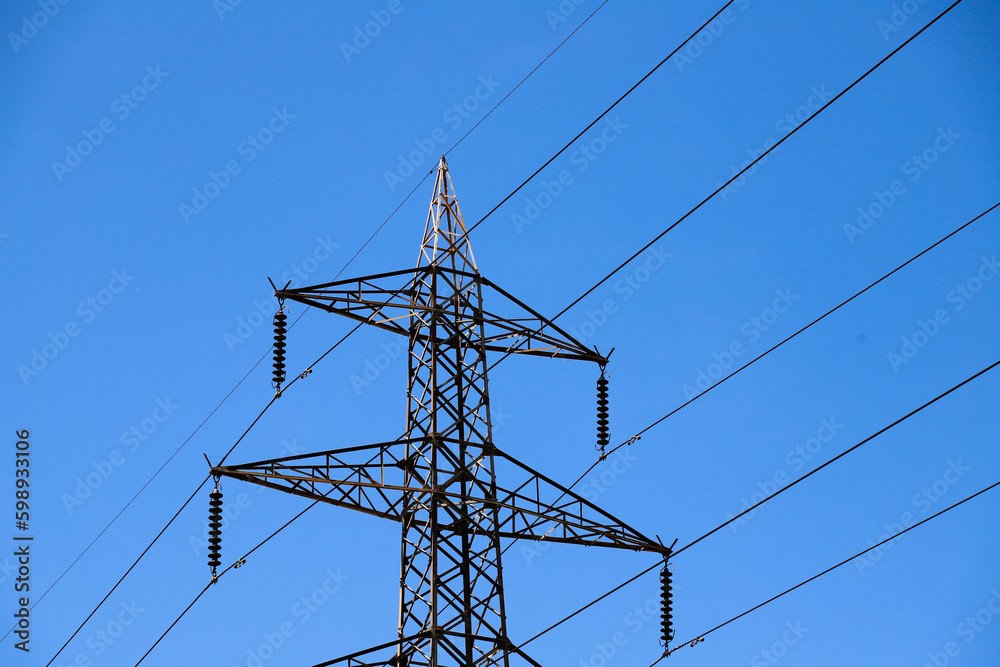 A power line tower with a blue sky in the background A power line tower with a blue sky in the background