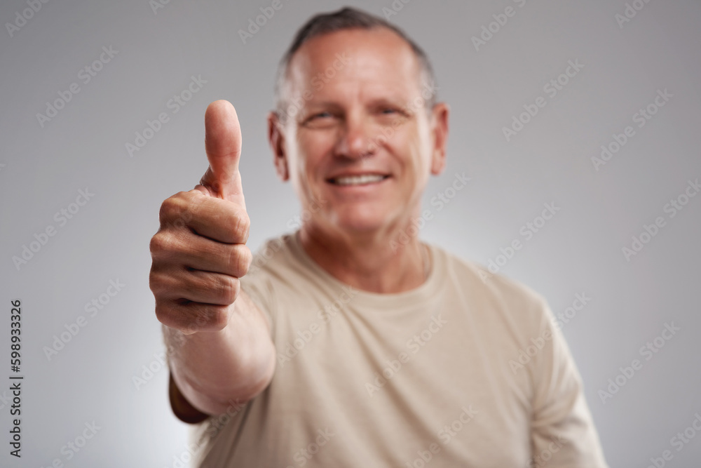 I cant not like this. a handsome mature man standing against a grey background in the studio and making a thumbs up gesture. I cant not like this. a handsome mature man standing against a grey background in the studio and making a thumbs up gesture.