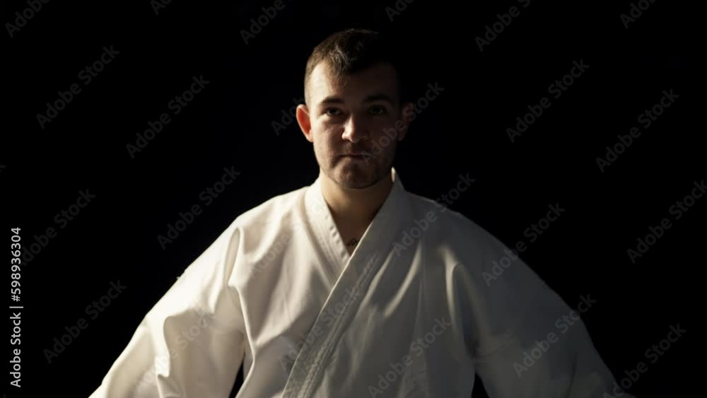 Man in white kimono bowing to opponent on black background, martial arts Man in white kimono bowing to opponent on black background, martial arts