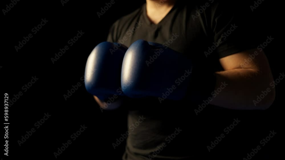 Closeup of man getting ready for boxing, wearing gloves on black background Closeup of man getting ready for boxing, wearing gloves on black background