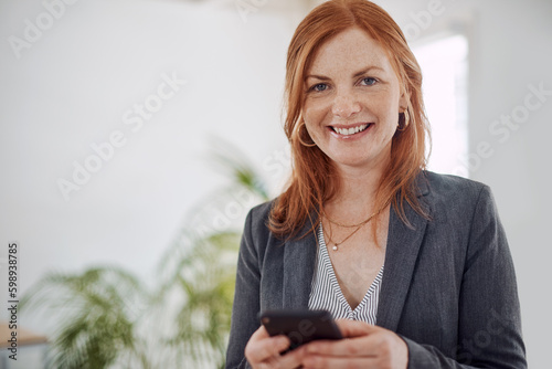 Just texting a client with some updates. Portrait of a mature businesswoman using a cellphone in an office.