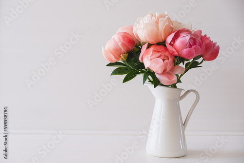 Fototapeta Naklejka Na Ścianę i Meble -  Beautiful bouquet of fresh coral peony flowers in full bloom in vase. Floral still life with blooming peonies. Negative space for text.