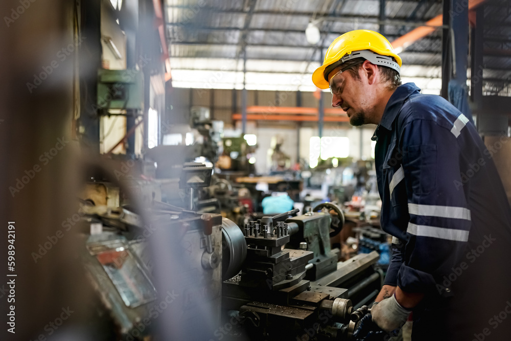 Lathe Operators Concentrated on Work. Worker in uniform and helmet works on lathe, factory. Industrial production, metalwork engineering, manufacturing. Lathe Operators Concentrated on Work. Worker in uniform and helmet works on lathe, factory. Industrial production, metalwork engineering, manufacturing.