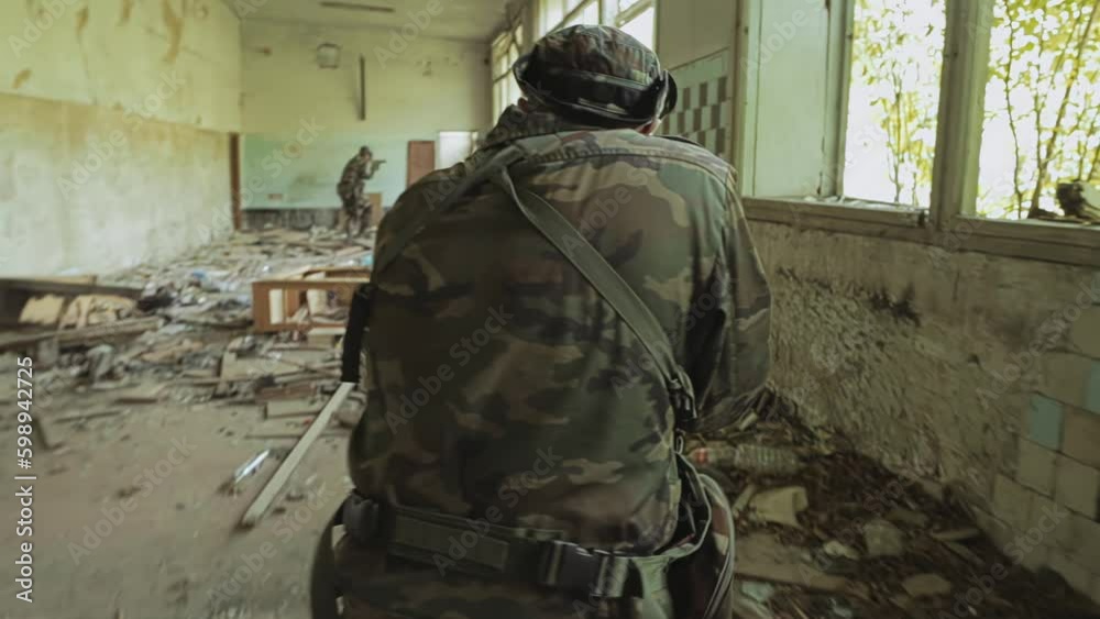 Two armed fighters are moving through the building in search of terrorists. Shooting from the back in dynamics Two armed fighters are moving through the building in search of terrorists. Shooting from the back in dynamics