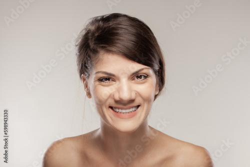 Portrait of a beautiful girl with happy face expression. Smiling lady against gray background.