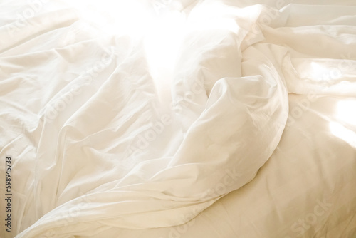 Full frame of White bedsheets in morning light, warm color. Messy of fabrics. Surface and texture background.