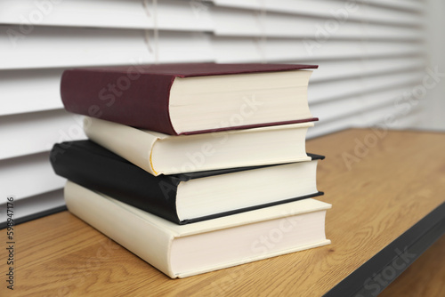 Stack of hardcover books on wooden table indoors  closeup