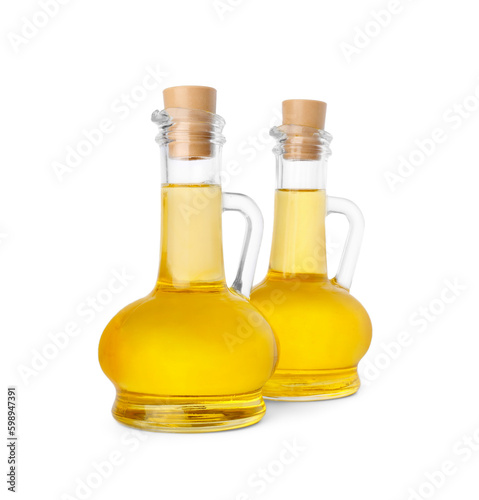 Glass jugs of cooking oil on white background