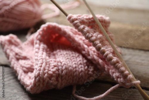 Pink knitting and needles on wooden table, closeup