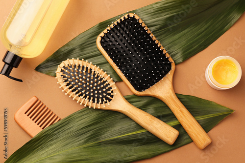 Flat lay composition with wooden hairbrushes and cosmetic products on light brown background