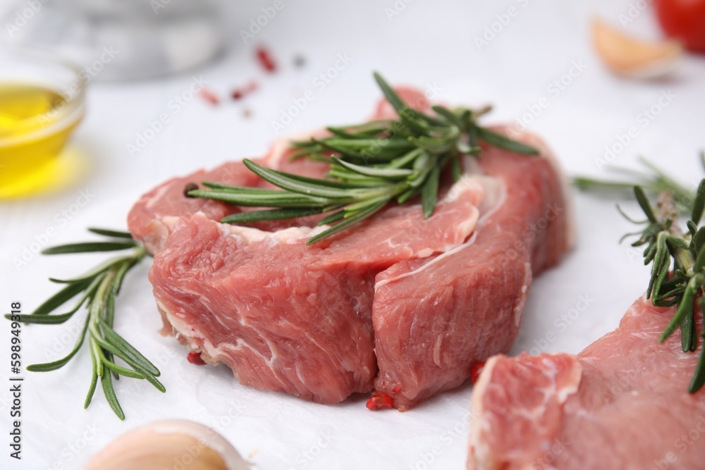Fresh raw meat with rosemary on parchment paper, closeup Fresh raw meat with rosemary on parchment paper, closeup