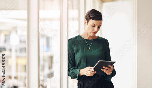 Technology keeps her ahead of the game. an attractive young businesswoman using her tablet while standing in the office.