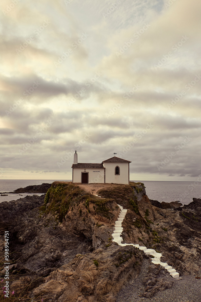 Pequeña ermita blanca construida sobre una roca en la costa gallega