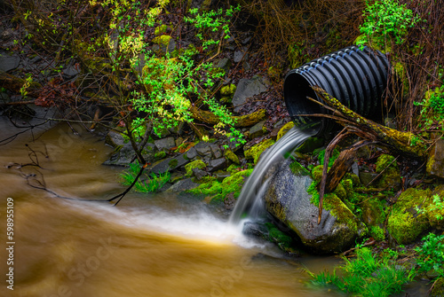 A slow shutter speed blurs the spring melt water running out of the drainage pipe and into Sage Creek in Windsor in Upstate NY.   Melting snow finds its way into the creek anthen into the Susquehanna. photo