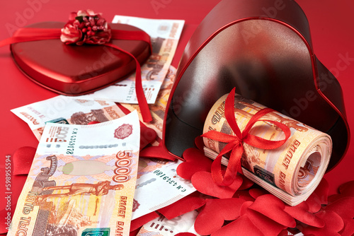 Russian rubles on red background, bundle of five thousand banknotes with red ribbon in heart box, money gift concept