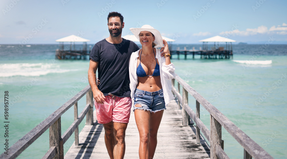 We havent been everywhere but its on our list. a happy young couple walking arm in arm down a boardwalk during a vacation together.
