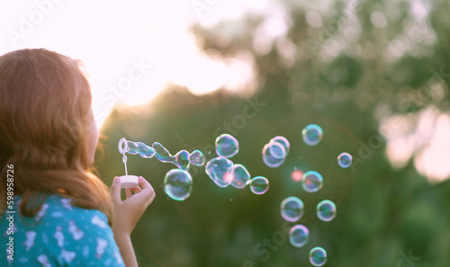 abstract blurred natural background with girl blowing soap bubbles outdoor. dreaming, harmony peaceful atmosphere. Happy childhood concept. template for design
