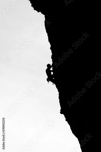 silhouette of a man climbing a rock, black and white image © unesthetic