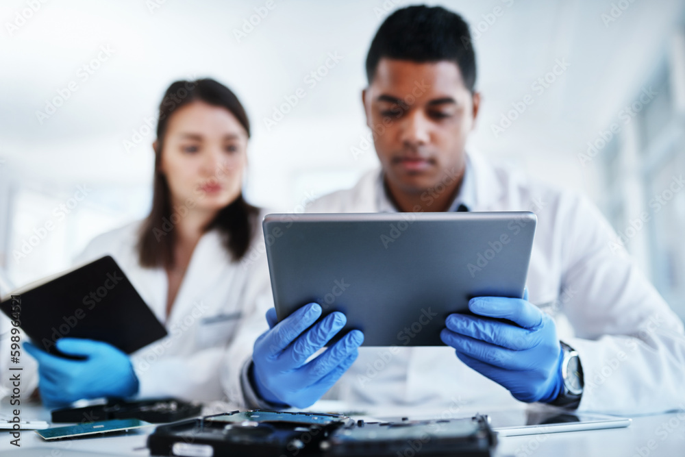 Obraz premium Whats tech support without cutting edge technology. a young man and woman using a digital tablet while repairing computer hardware in a laboratory.