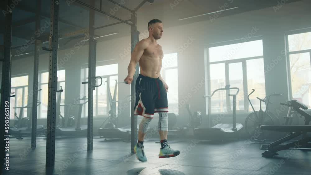 Full shot of athletic young man with naked torso jumping on the rope in gym preparing for boxing match. Sportsman trains alone in fully-equipped gym. High quality 4k footage Generative AI Full shot of athletic young man with naked torso jumping on the rope in gym preparing for boxing match. Sportsman trains alone in fully-equipped gym. High quality 4k footage Generative AI
