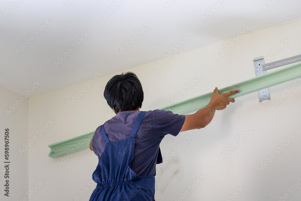 Young repairman fixing air conditioner unit, Asian technician man installing an air conditioning in a client house, Maintenance and repairing concepts Young repairman fixing air conditioner unit, Asian technician man installing an air conditioning in a client house, Maintenance and repairing concepts