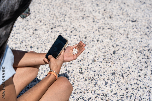 mujer tomando foto a arena blanca en su mano con el móvil photo